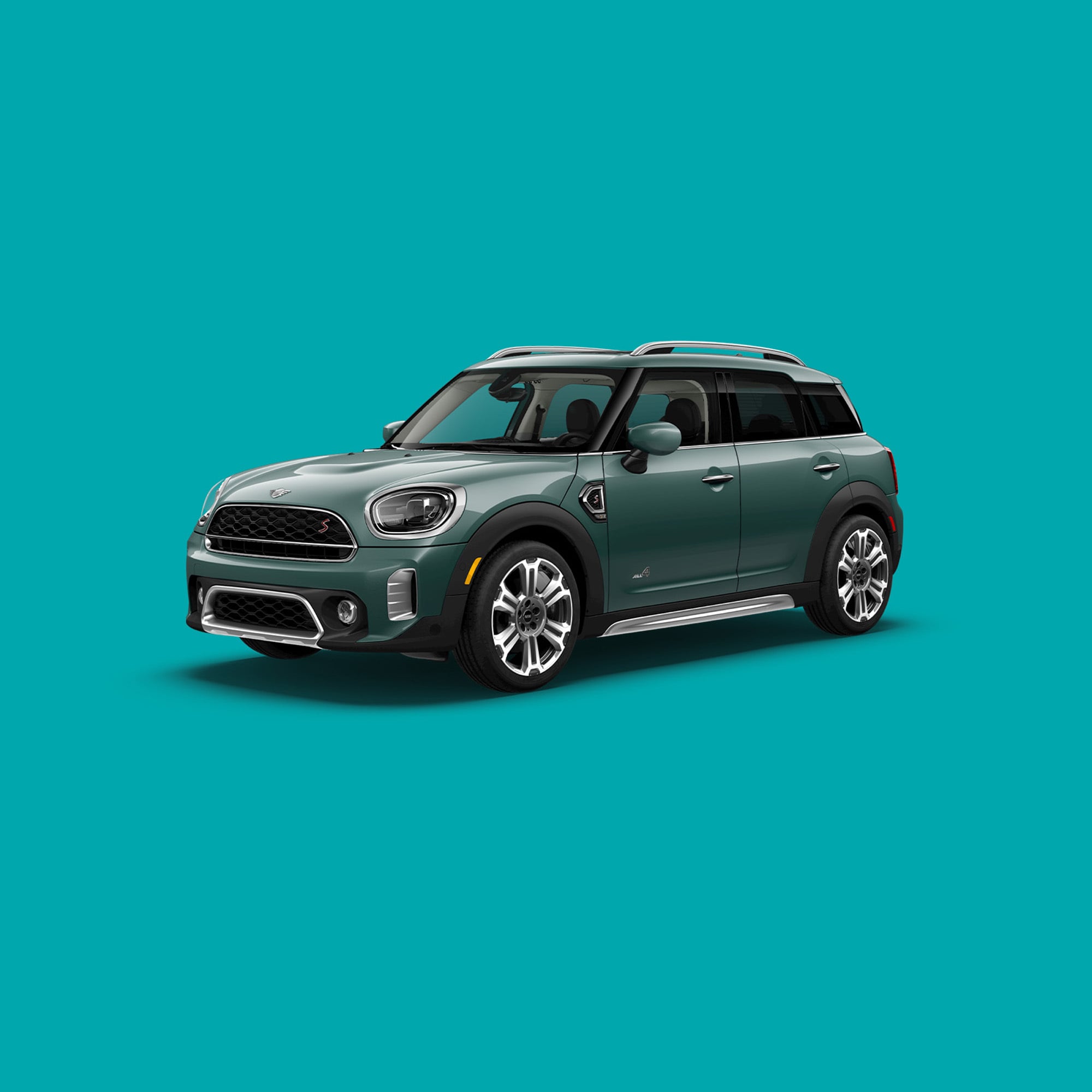 Angled front-to-rear view of a MINI Countryman S ALL4 in Sage Green metallic, against a turquoise backdrop.