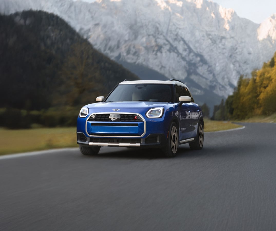 A MINI Countryman S ALL4 driving with tall mountains in the background.