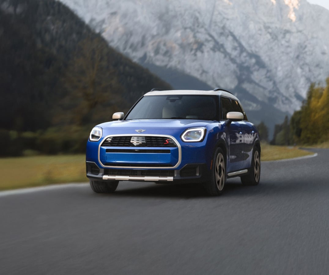 A MINI Countryman S ALL4 driving with tall mountains in the background.