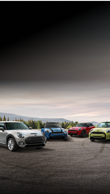 Five MINI vehicles of different exterior body colors parked on a brick surface and facing different directions with glass architecture in the background.