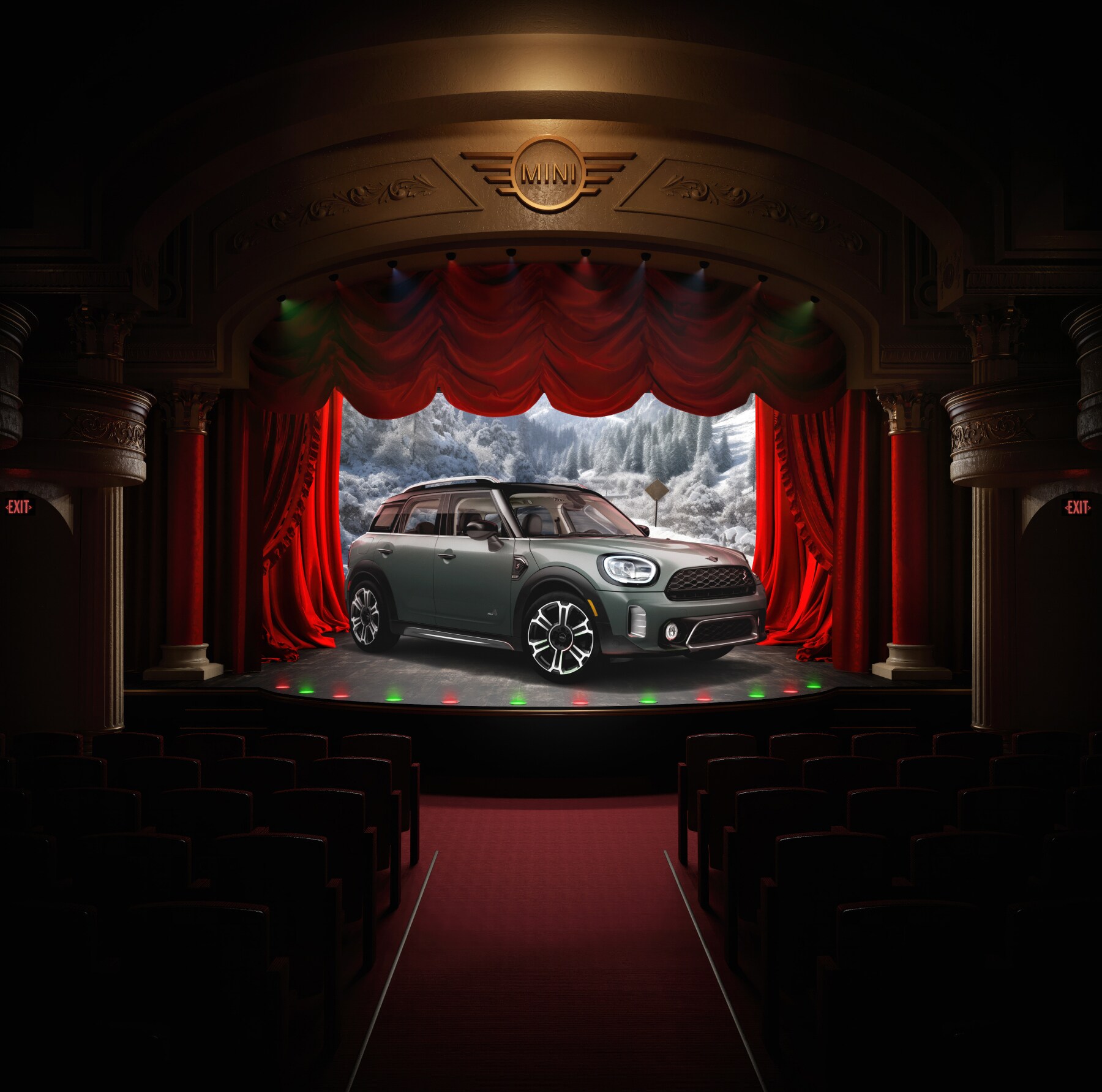 Three-quarters front view of a green MINI Countryman parked in the center of a stage facing towards the audience, plus red curtains behind it enclosing a wintery outdoor forest setting in the background.
