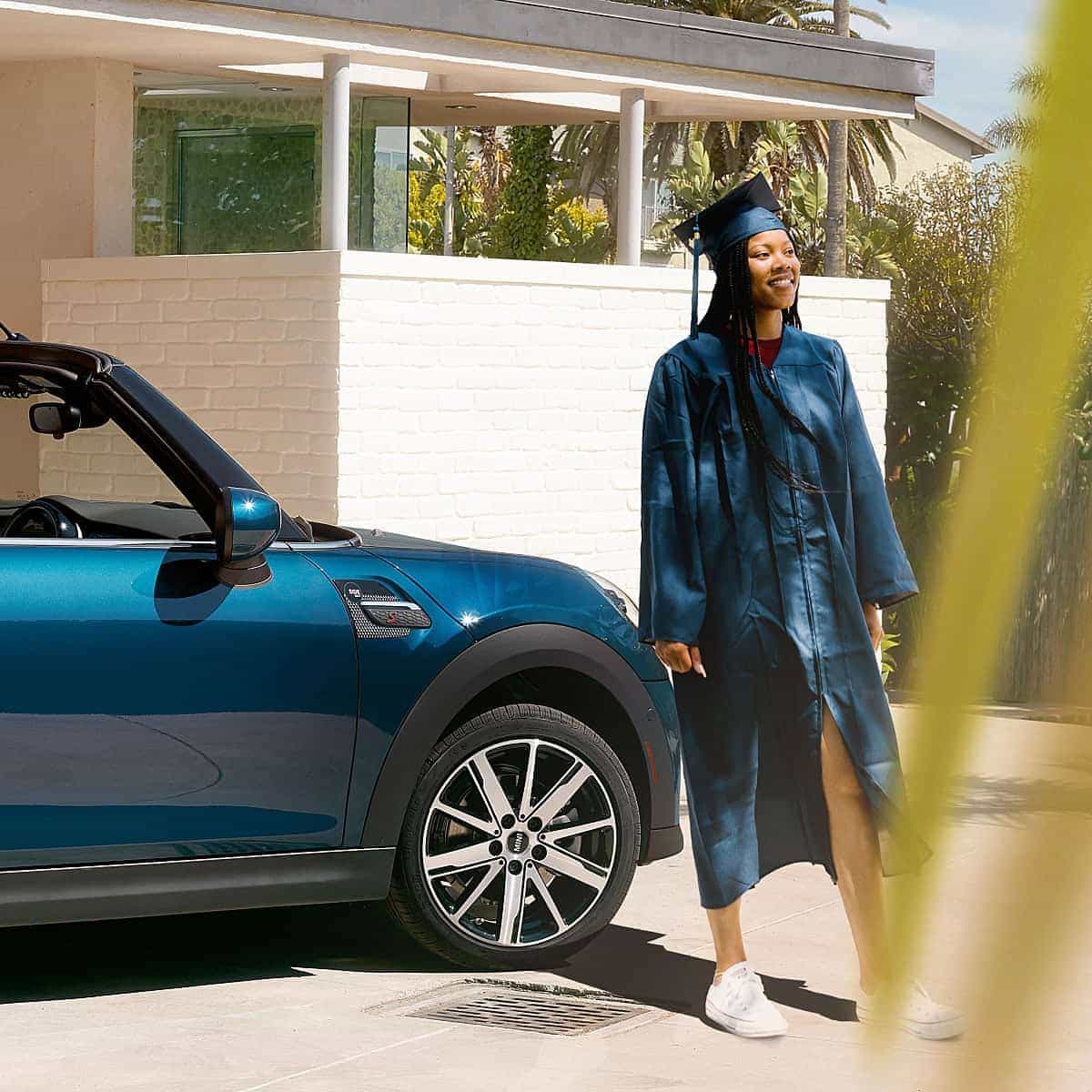 A new graduate in front of her MINI in a tropical setting