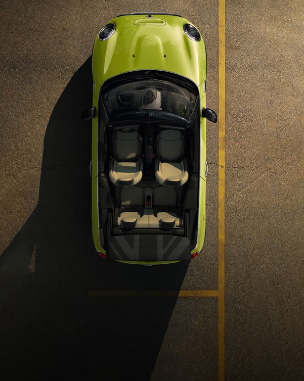 Overhead view of a yellow MINI Convertible parked in a parking space with its top folded down and shadows surrounding the vehicle.