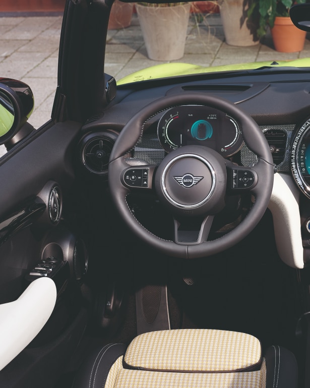 Closeup view of the steering wheel and dashboard inside a Convertible from the perspective of the driver’s seat.